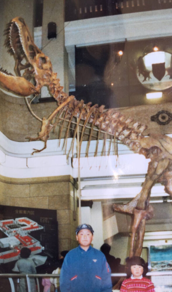 恐竜の骨格展示を背景に、お兄さんとともに。